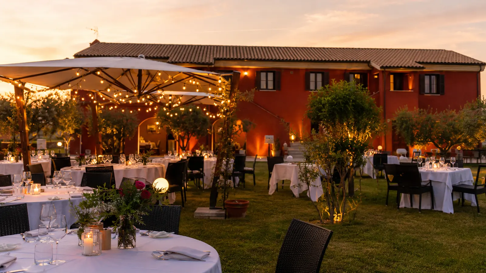 Il giardino del casale al tramonto con ombrelloni e luci accese